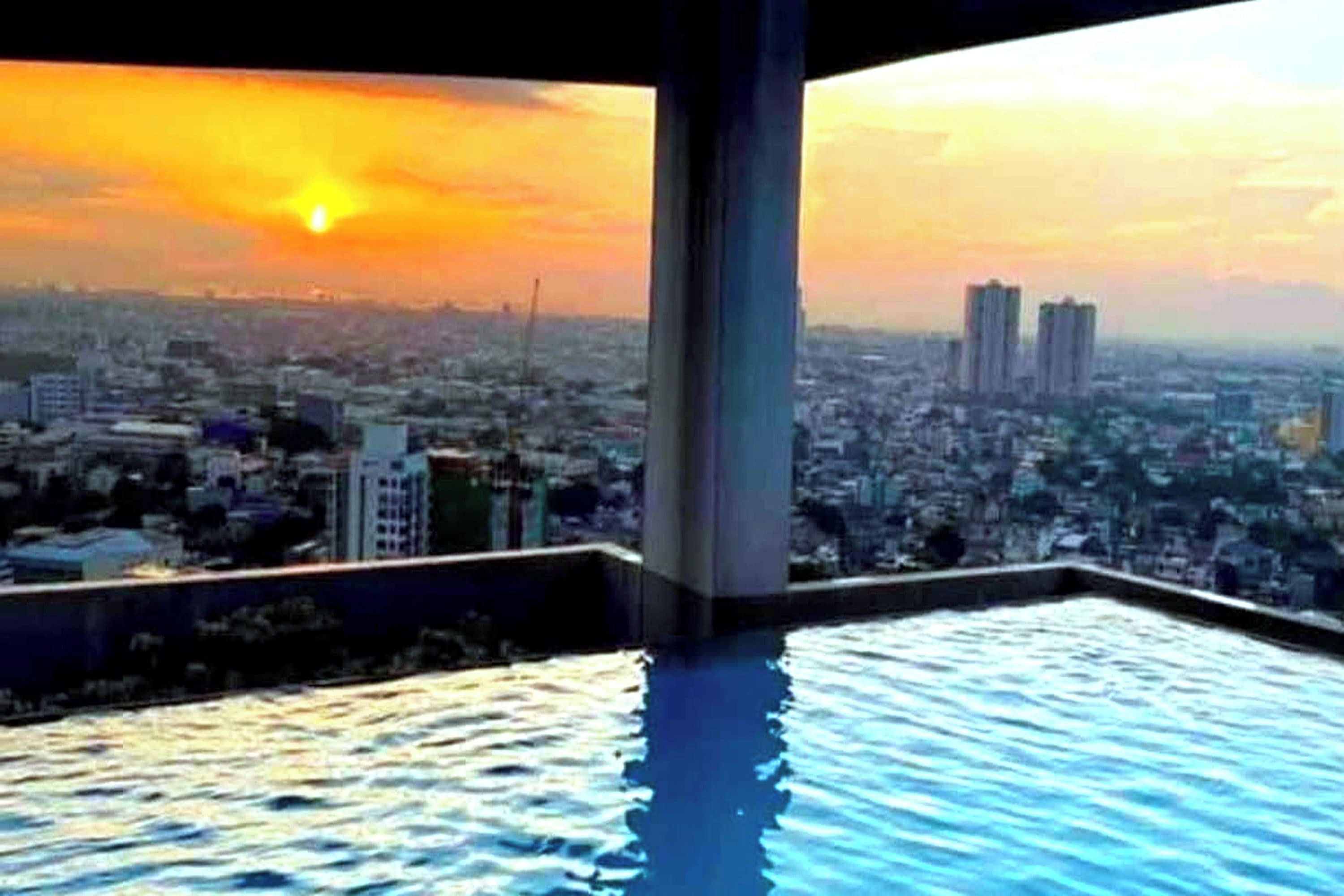 An infinity pool with a cityscape view at sunset.