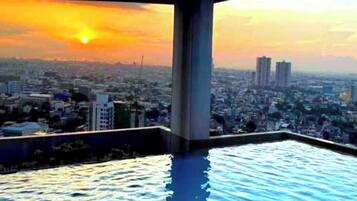 An infinity pool with a cityscape view at sunset.