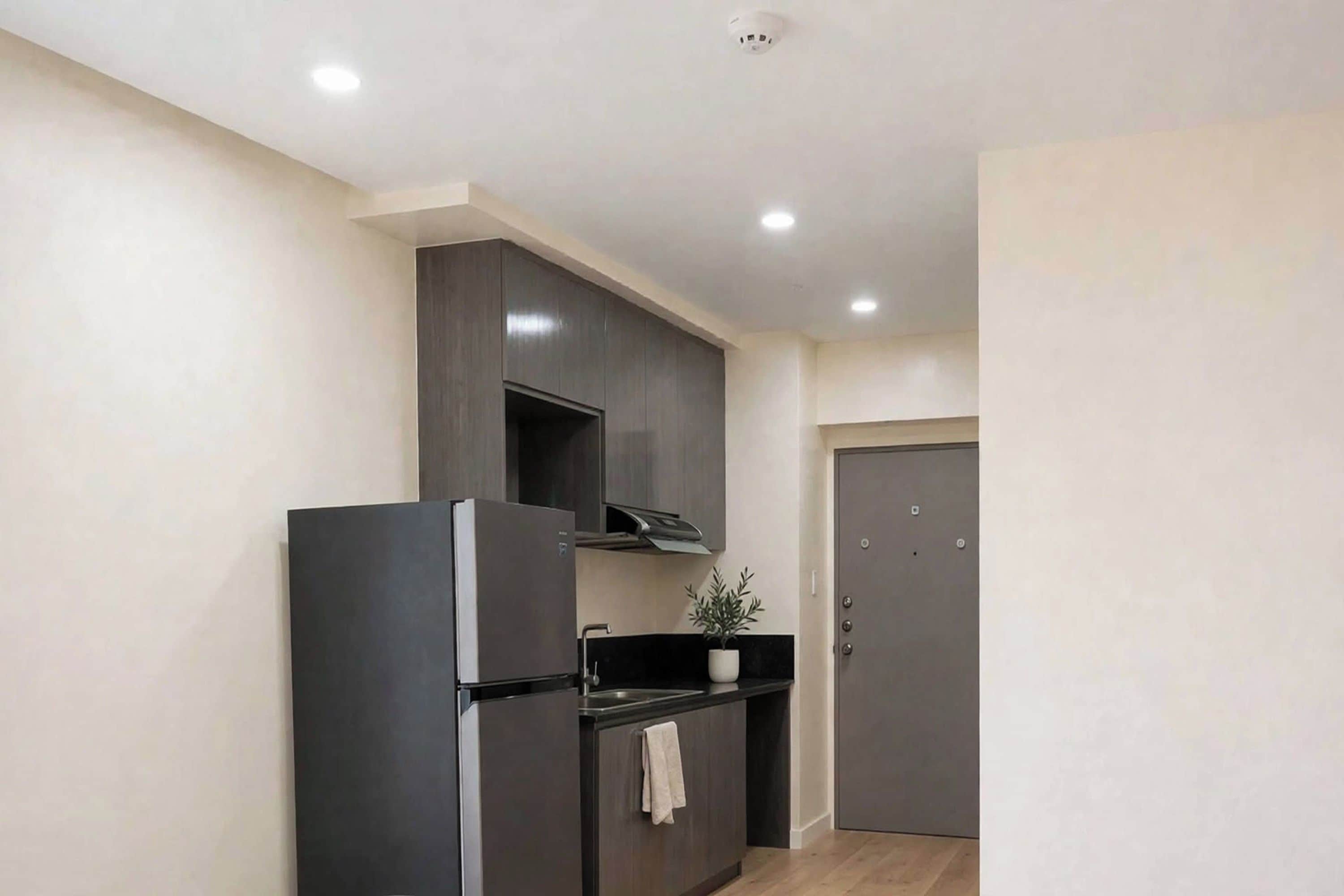 A compact kitchen with a built-in refrigerator, a stove, and a dark wooden cabinet.