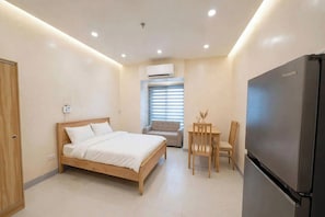 Ein gemütliches Schlafzimmer mit einem Bett, einem Esstisch mit Stühlen, einem Kühlschrank und einer Klimaanlage.