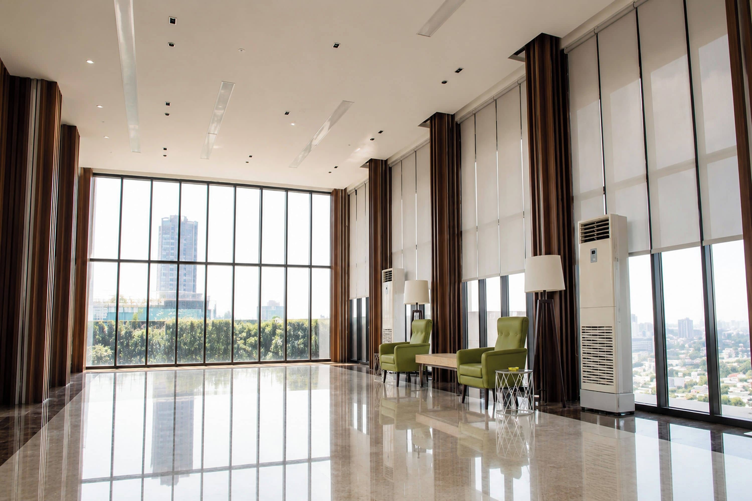 A spacious lobby with large windows, a high ceiling, and modern furnishings.