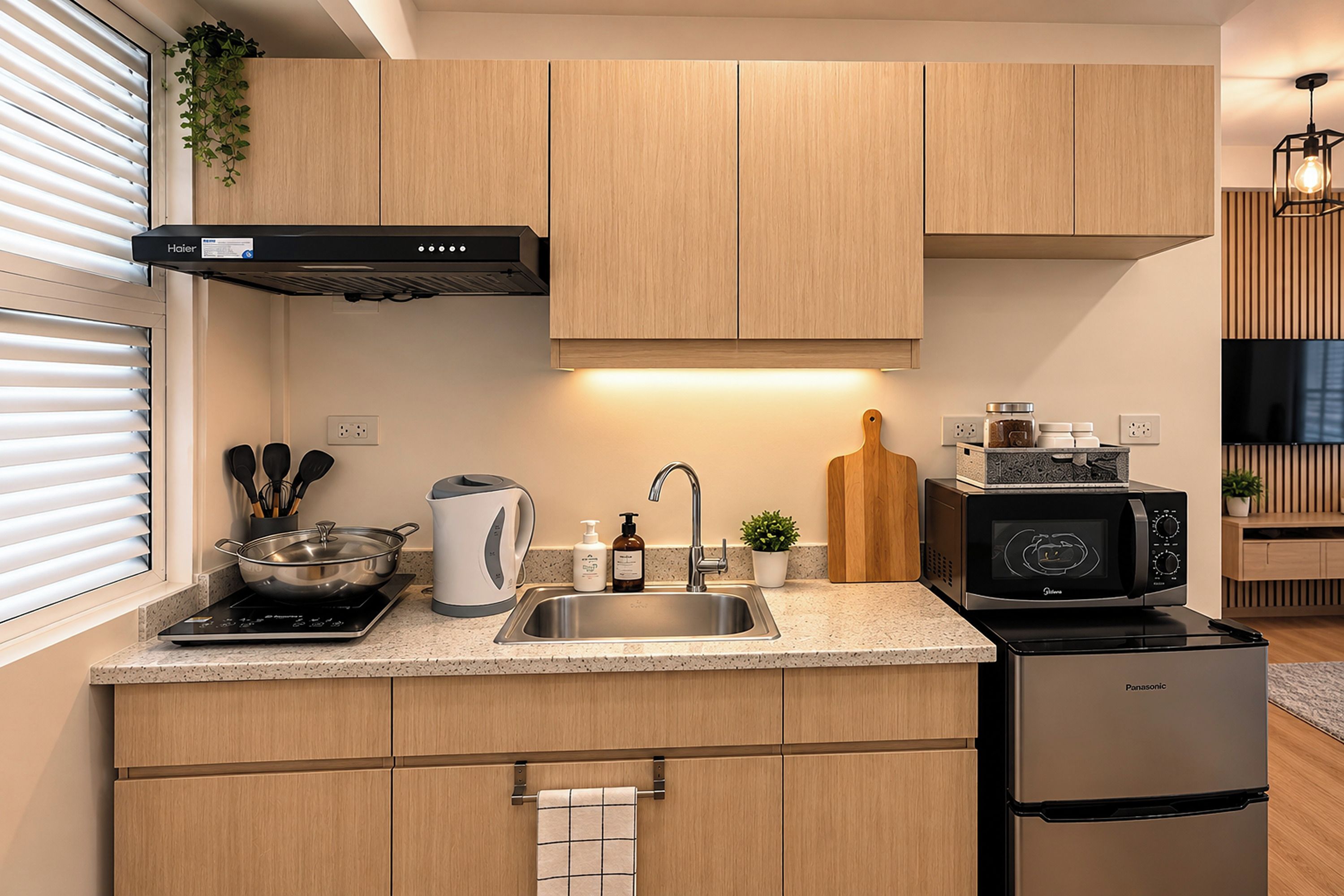A modern kitchen with wooden cabinets, a stainless steel sink, a kettle, a toaster, a microwave, and a refrigerator.