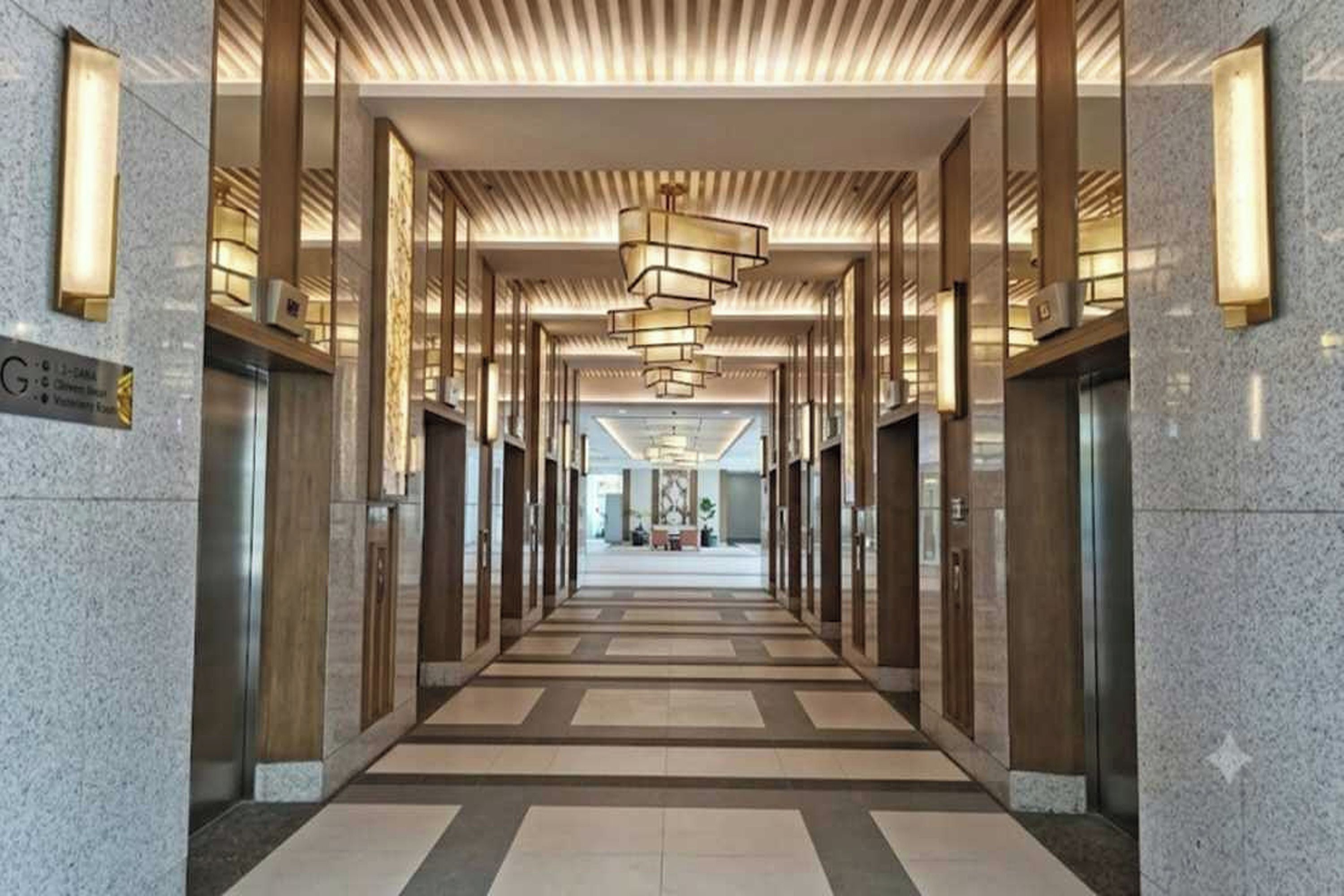 A corridor with a modern design, featuring a patterned floor and a series of elevators.