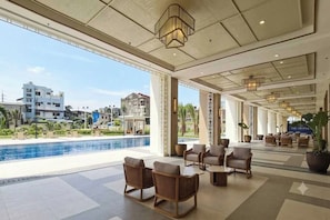A hotel lobby with a pool view, outdoor seating, and a modern design. - Cozy 1Br Staycation Unit At The Celandine, Balintawak, Quezon City (Quezon City)