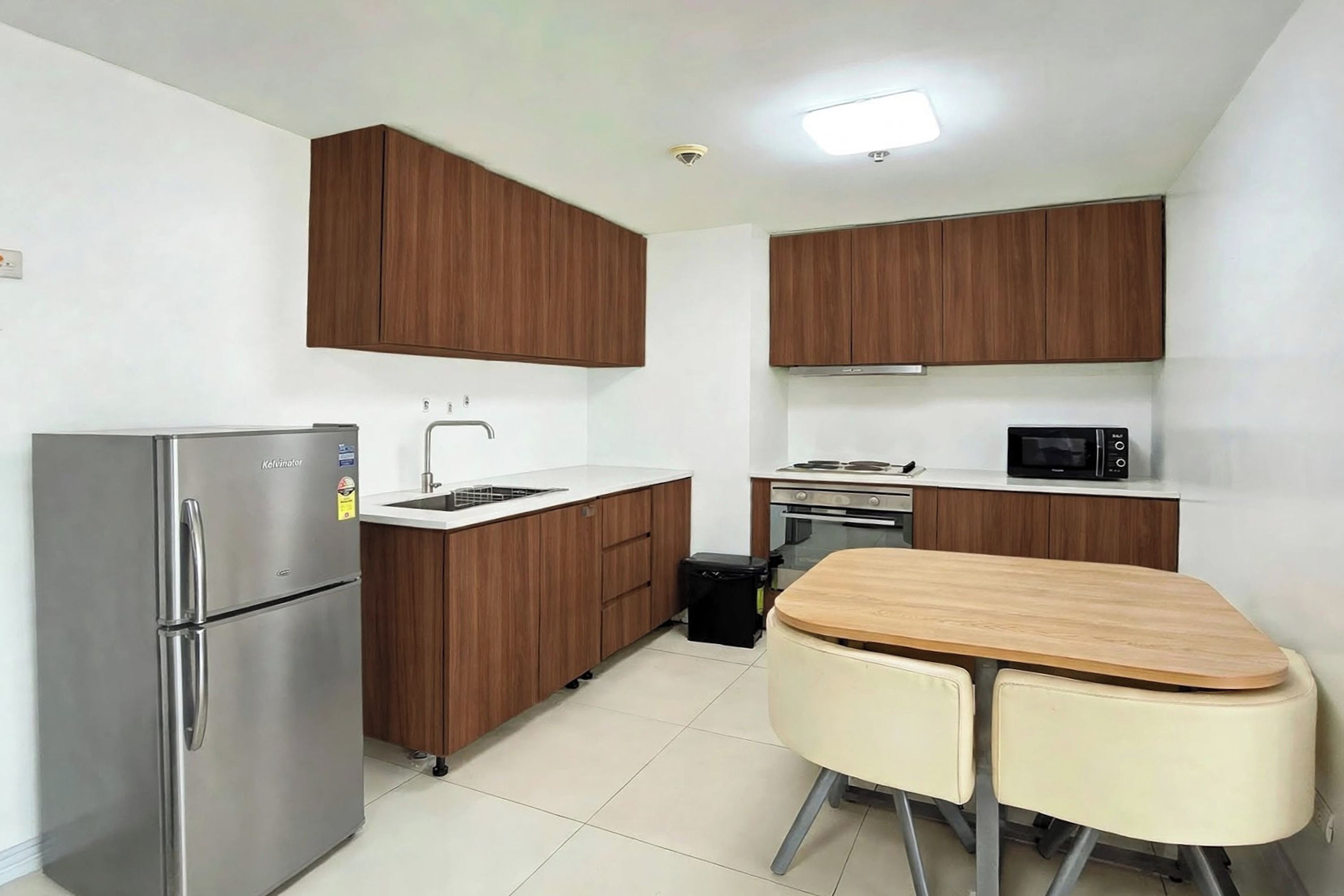 A compact kitchen with a refrigerator, stove, microwave, and a small dining table with chairs.