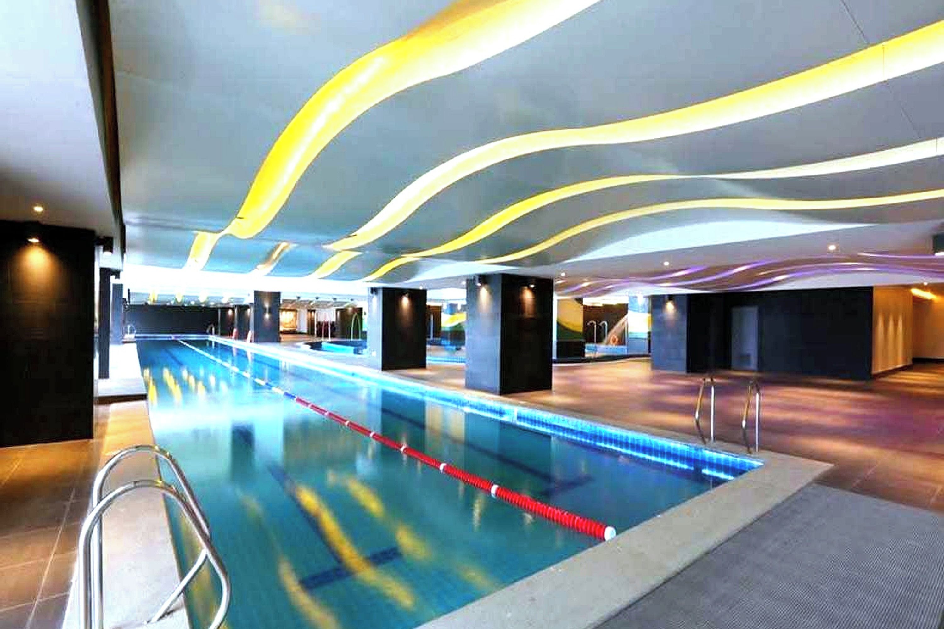 A swimming pool with a modern design, featuring a long, straight layout and a pool ladder on one side.