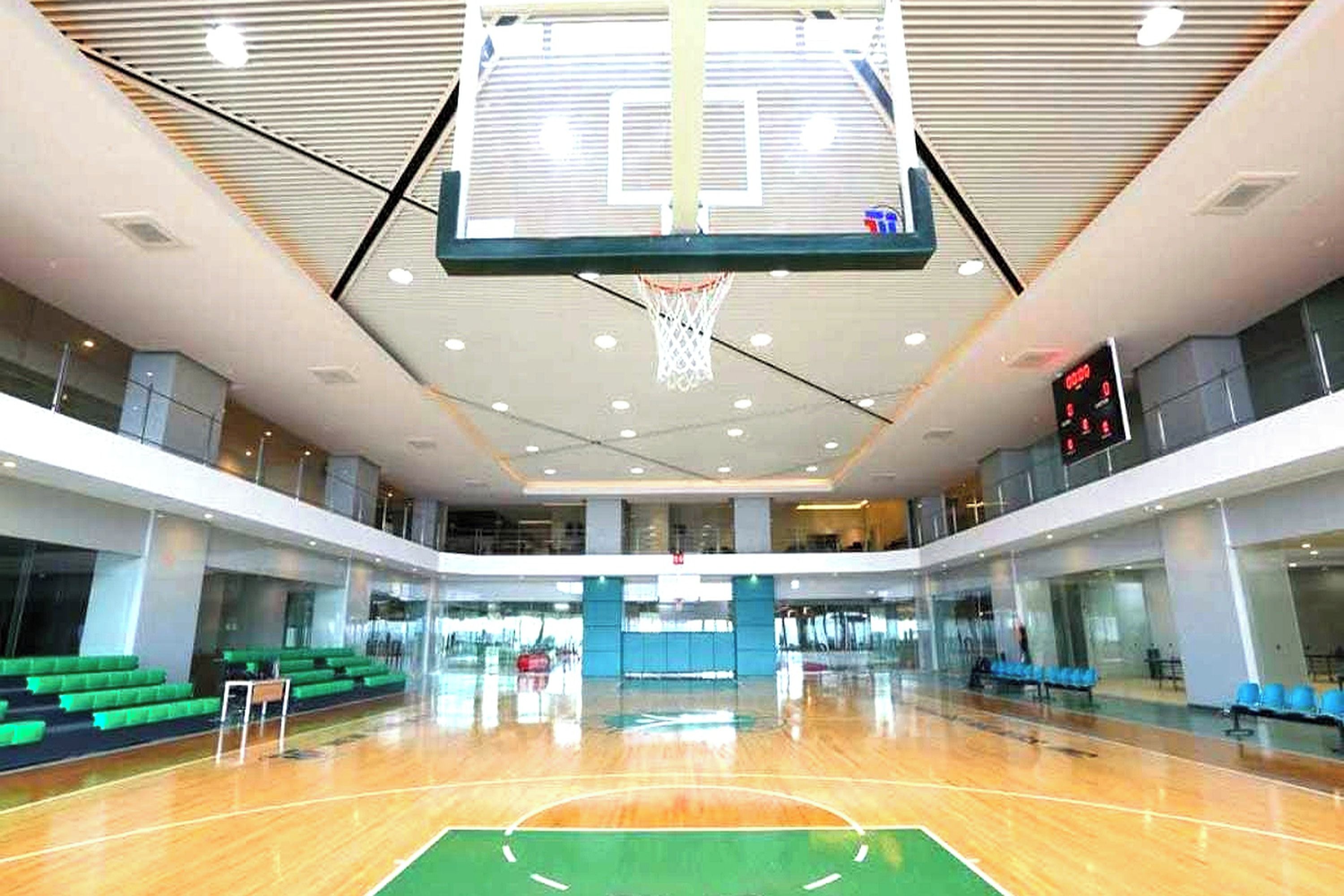 Una cancha de baloncesto cubierta con varios niveles, un marcador digital y zonas de asientos.