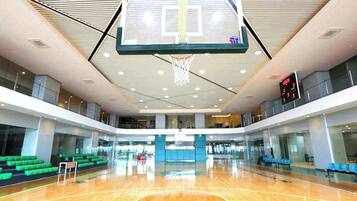 Una cancha de baloncesto cubierta con varios niveles, un marcador digital y zonas de asientos.