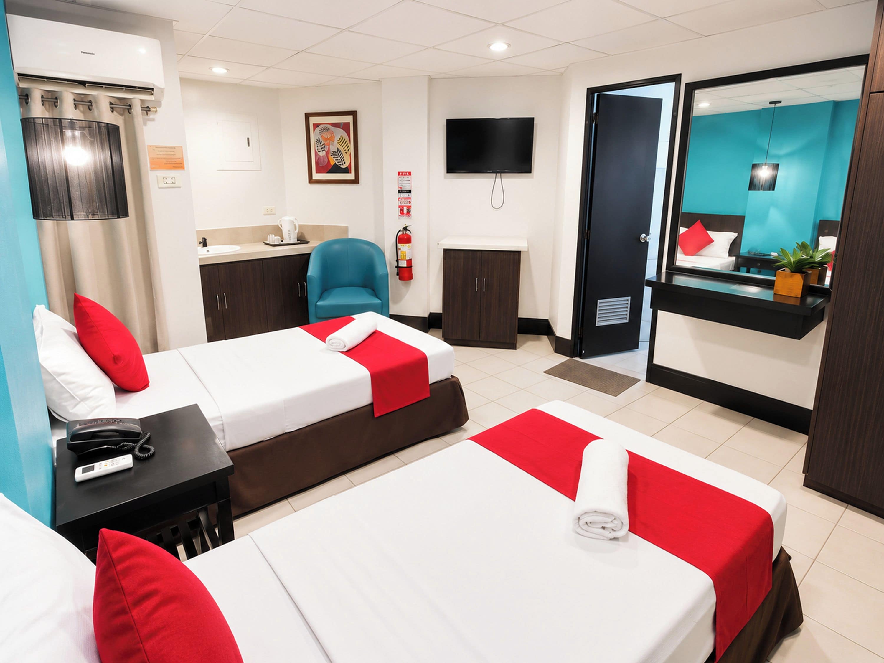Een hotelkamer met twee bedden, een bureau, een stoel, een televisie en een badkamer.