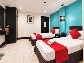 A hotel room with two beds, a desk, a phone, and a wall-mounted light fixture. - Orange Nest Hotel (Manila)