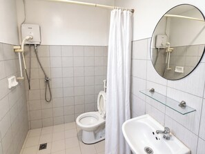 A bathroom with a toilet, a shower, a sink, and a mirror. - Orange Nest Hotel (Manila)