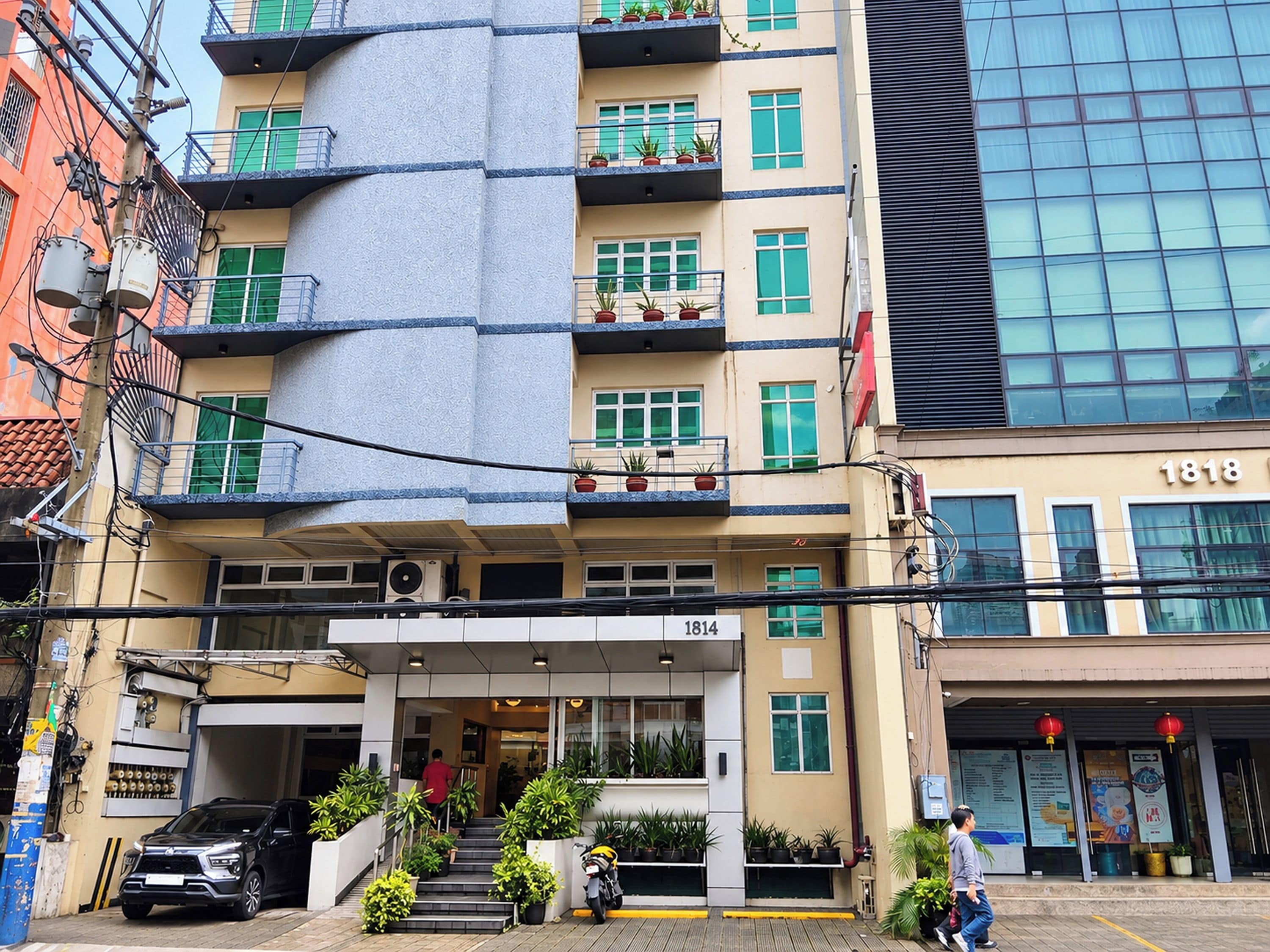 Um hotel com vários andares, fachada moderna, área de estar externa e entrada visível.