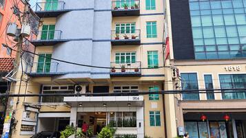 Um hotel com vários andares, fachada moderna, área de estar externa e entrada visível.