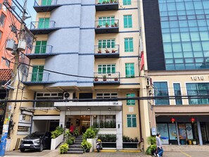 Un hotel de varios pisos con fachada moderna, zona de estar al aire libre y una entrada visible.