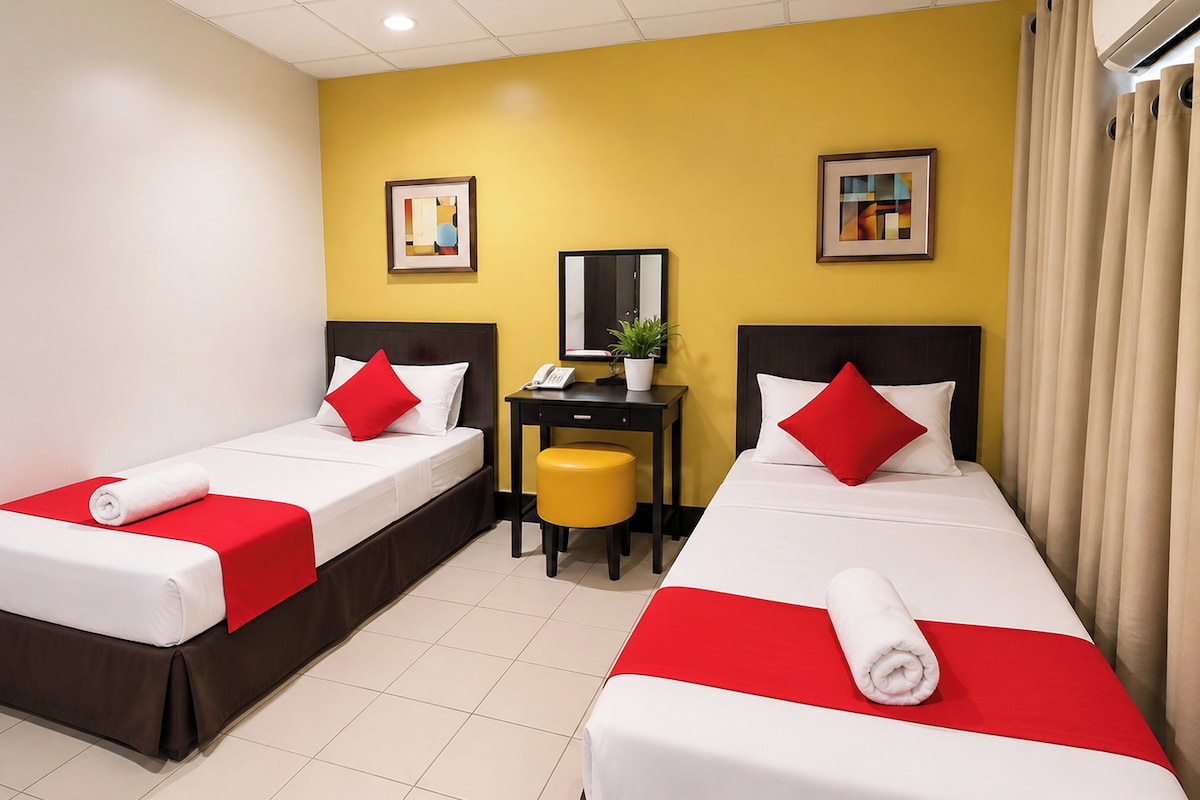 A hotel room with two beds, a desk, and a chair.