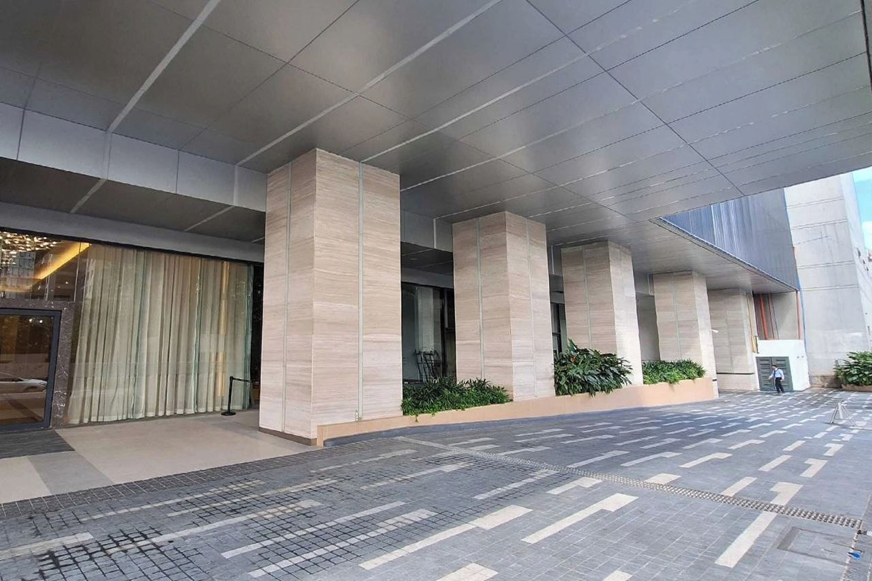 A modern building with a covered entrance and a tiled ground.