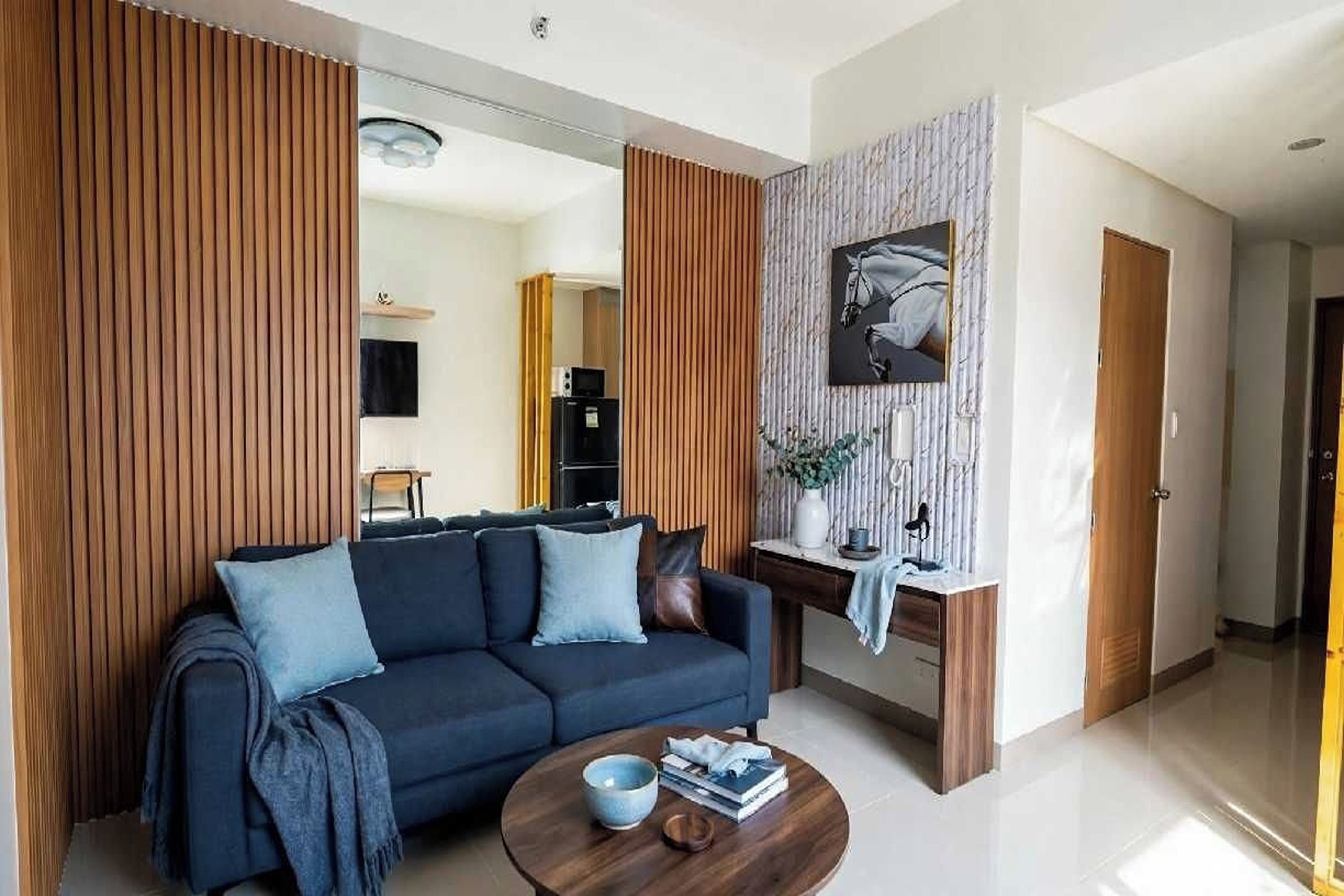 A modern living room with a dark sofa, a coffee table, and a decorative wall piece.
