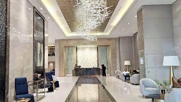 A modern lobby with a central reception desk, seating areas, and a decorative ceiling light fixture.