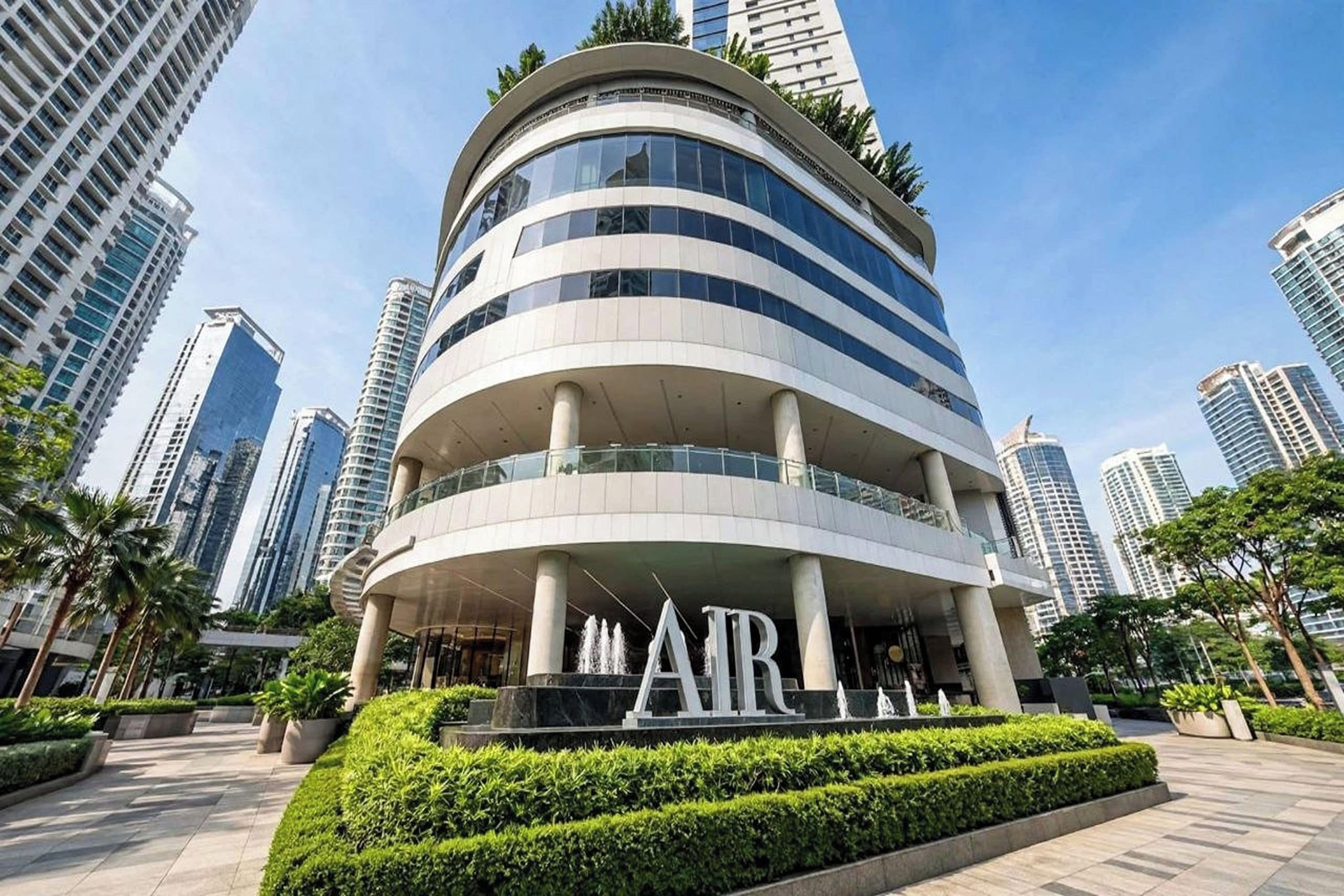 A modern multi-story building with a curved facade, surrounded by other high-rise buildings.