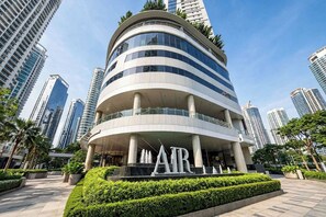 Un edificio moderno de varios pisos con fachada curva, rodeado de otros edificios altos.