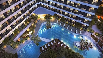 Un hotel de varios pisos con una piscina en la azotea, varios balcones y un interior bien iluminado.