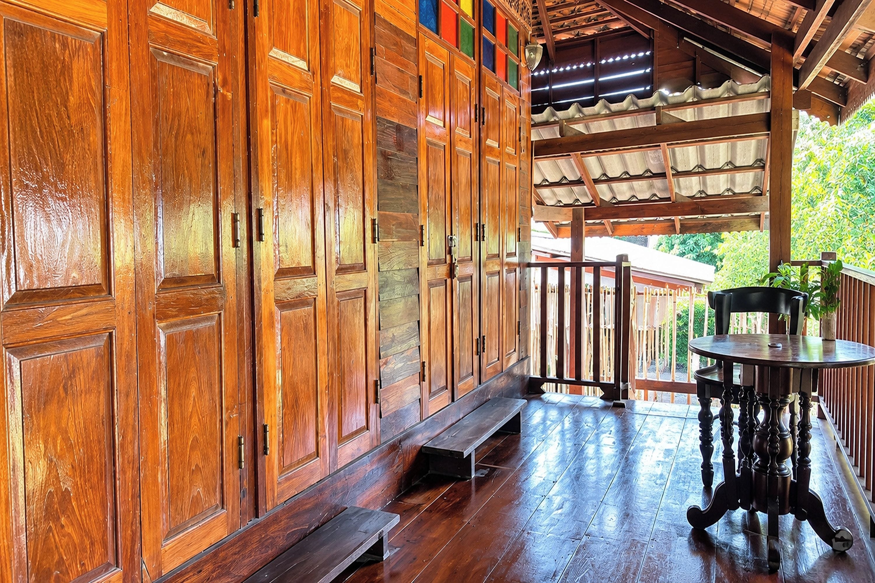 Un portico in legno con una panchina e un tavolo, vista su un giardino.