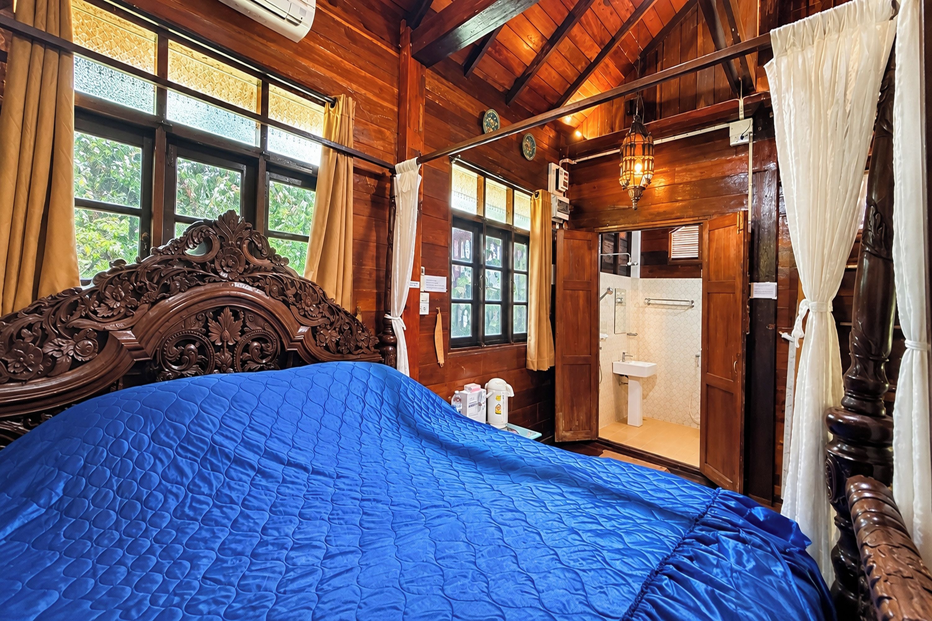 A wooden room with a bed, a window, a door, and a bathroom.