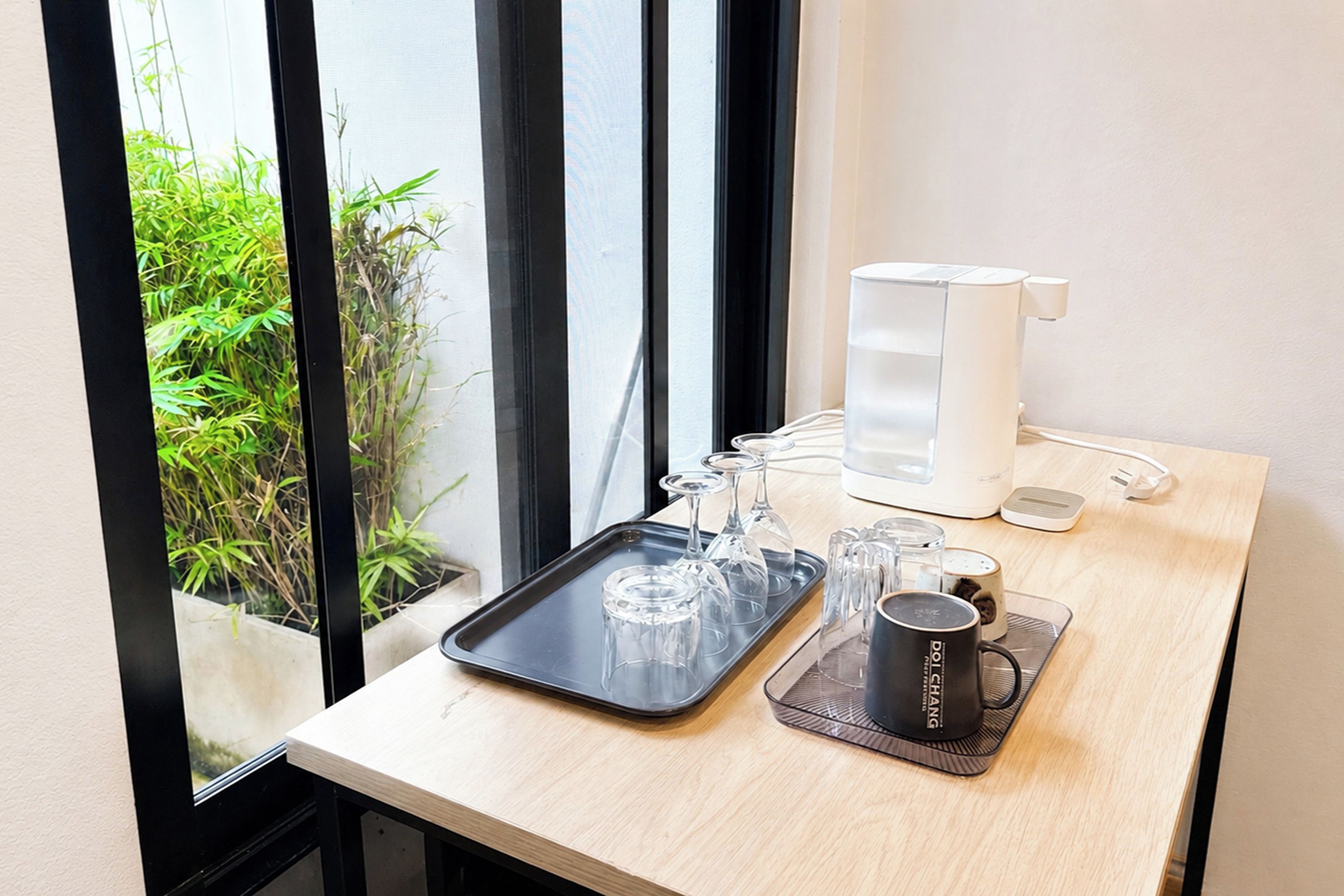 Una mesa con una bandeja que sostiene copas de vino, una cafetera y una taza.