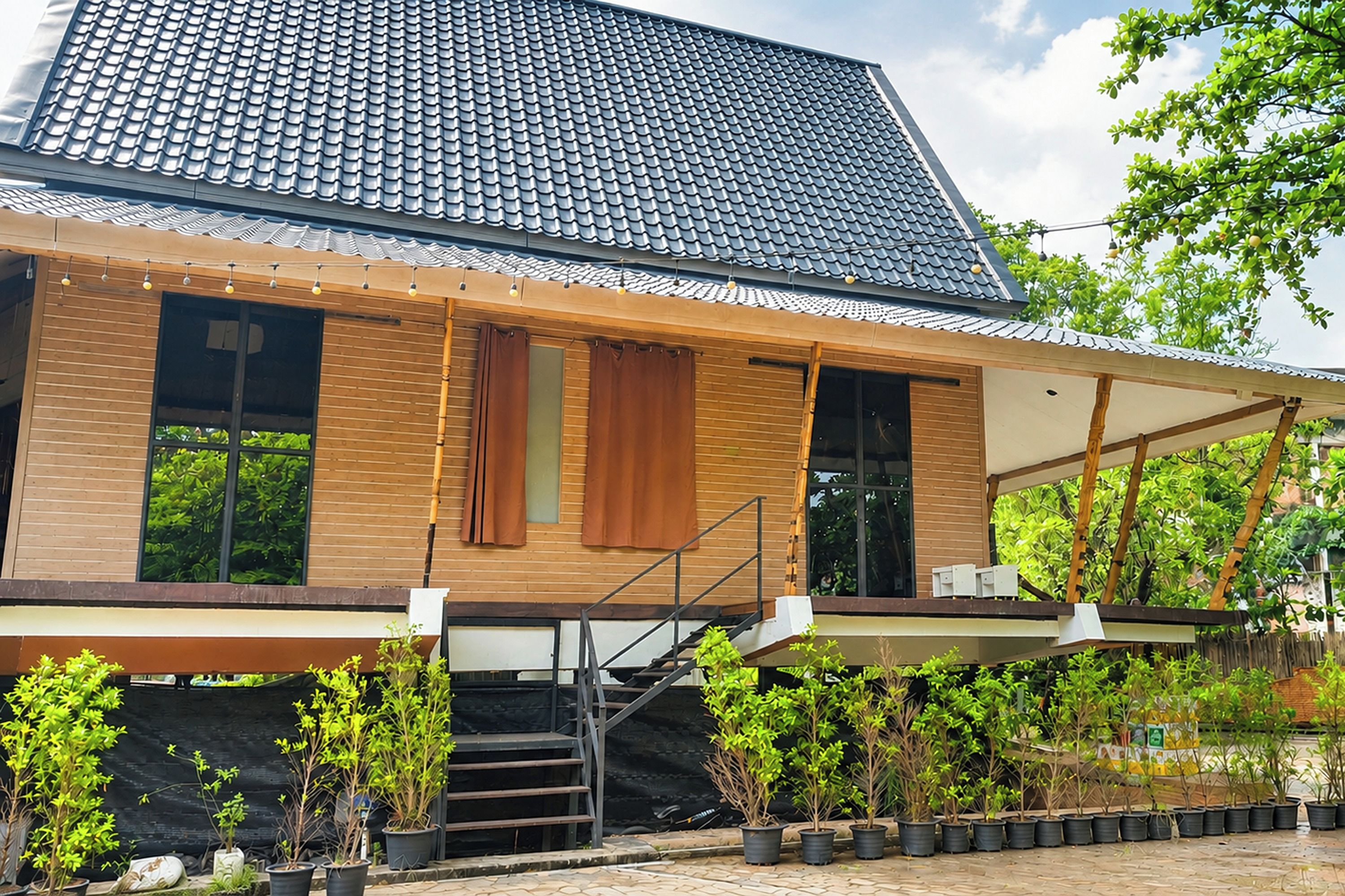 Una casa moderna con techo de tejas, revestimiento de madera y un porche cubierto con plantas en macetas.