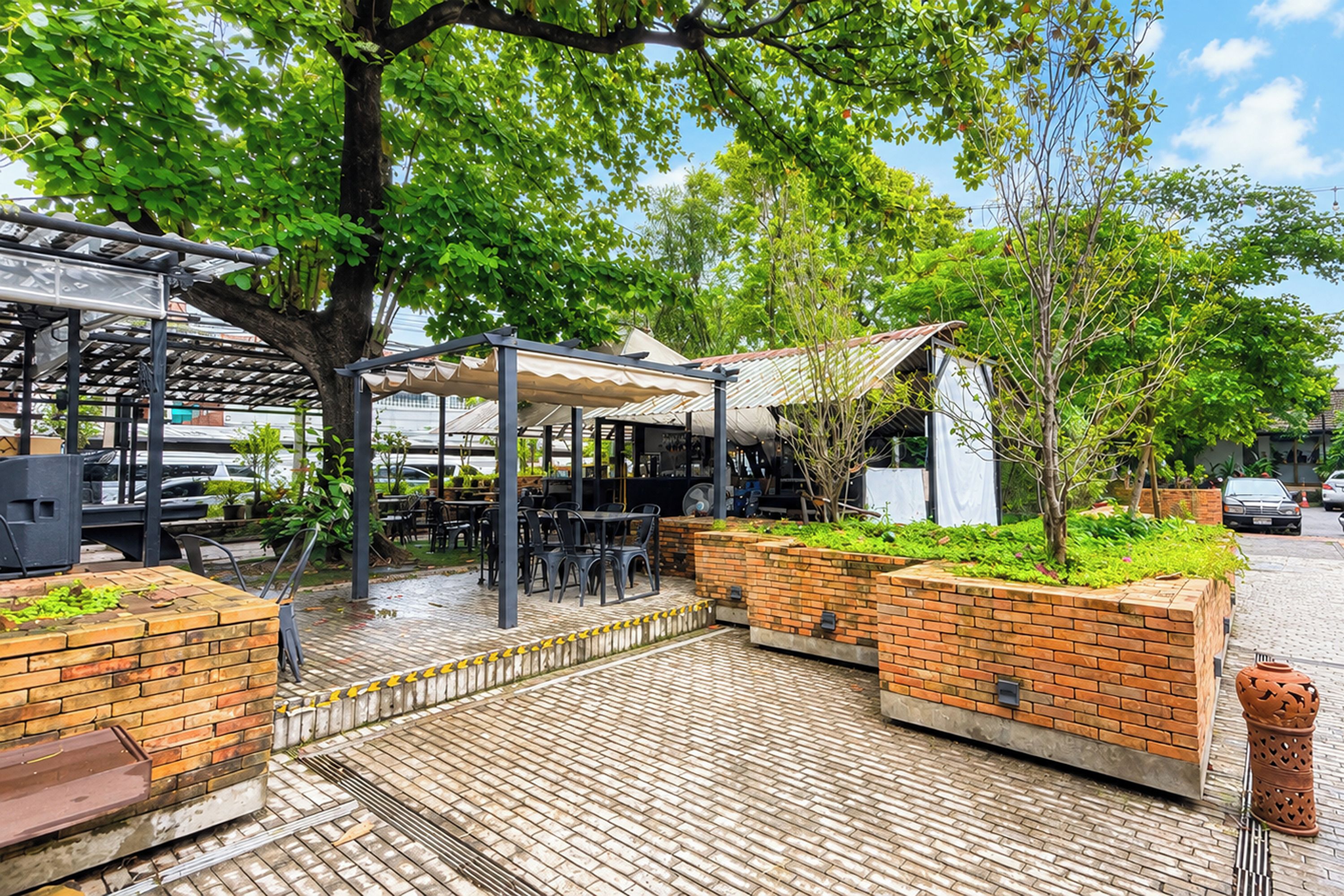 Un área de estar al aire libre con jardineras de ladrillo, un porche cubierto y un camino de ladrillo.