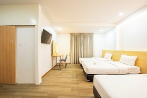 Una habitación de hotel con dos camas, un escritorio con silla, un televisor y una cortina.