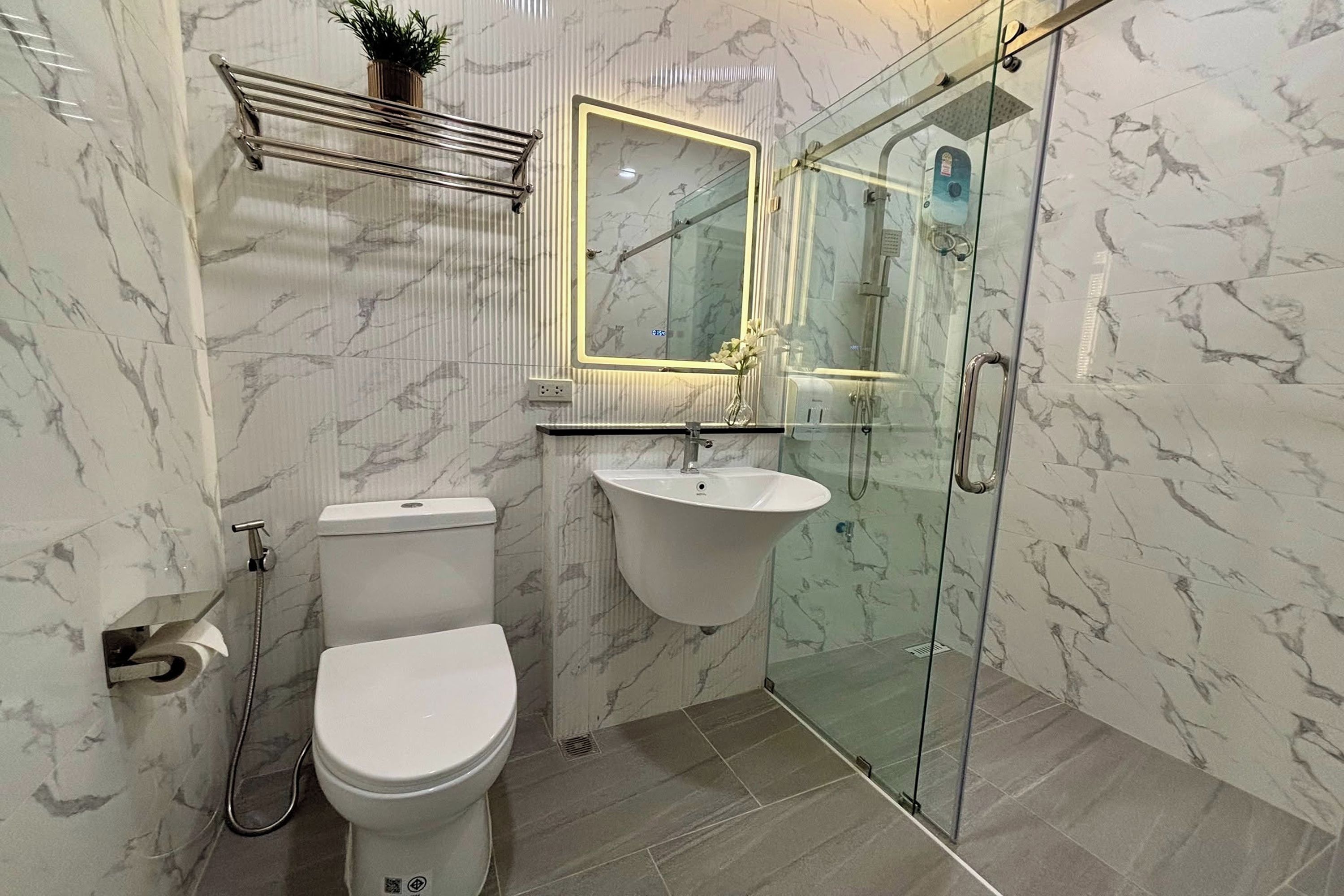 Un baño con inodoro, lavamanos y cabina de ducha de vidrio.