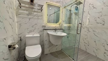 Un baño con inodoro, lavamanos y cabina de ducha de vidrio.