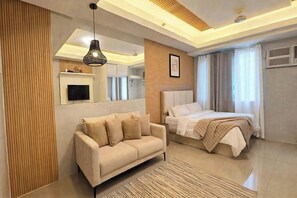 Un dormitorio moderno con sofá, cama, televisor montado y lámpara de techo.
