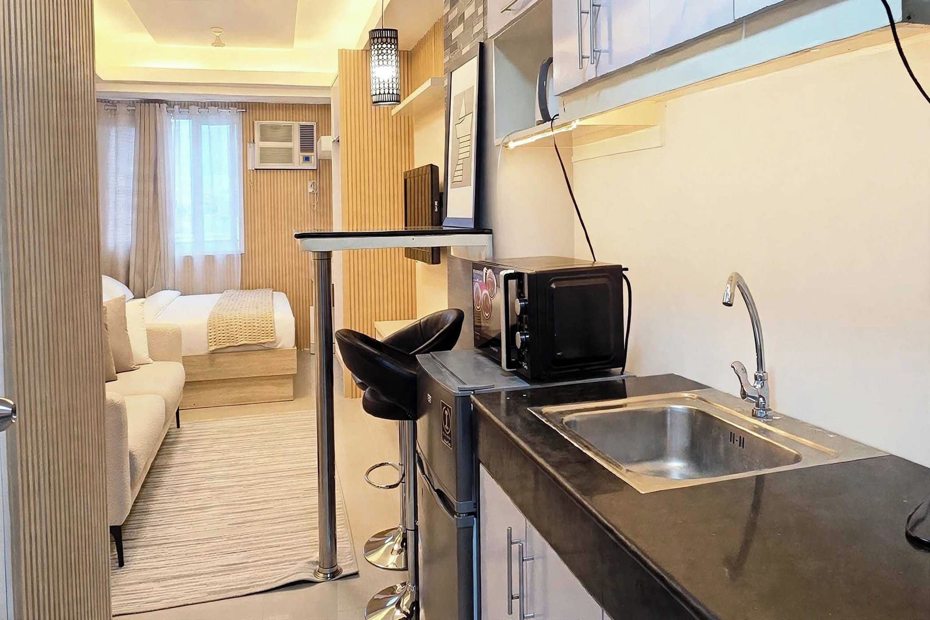 A compact kitchenette with a microwave, sink, and a small dining area with a chair.
