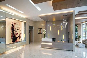 Un vestíbulo moderno con una recepción, una obra de arte grande en la pared y un candelabro.