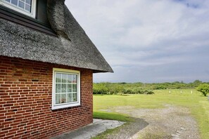 A brick house with a thatched roof and a window. - Friesenhaus Carl Jensen Holiday Apartment 1 (Wenningstedt-Braderup)