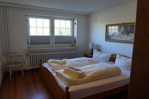 Une chambre à coucher avec un lit double, une chaise, un radiateur et une fenêtre.