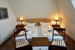A hotel room with two beds, a small table, two chairs, and bedside lamps. - Holiday apartment with 4 bedrooms (Wenningstedt-Braderup)