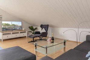 Ein modernes Wohnzimmer mit einem Glastisch, einem Fernseher und einem Sofa.