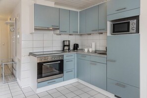 Eine kleine Küche mit hellblauen Schränken, einem Einbauofen, einer Mikrowelle und einer Kaffeemaschine.