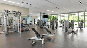 Ein Fitnessstudio mit verschiedenen Trainingsgeräten, darunter Kraftgeräte, Kurzhanteln und Cardiogeräte.