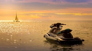 Un jet ski sobre aguas tranquilas con un atardecer de fondo.