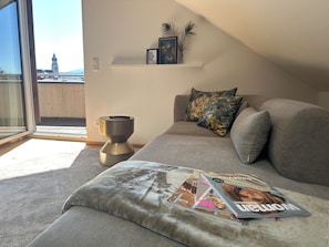 Una sala de estar moderna con un sofá, una revista y un estante pequeño con objetos decorativos.