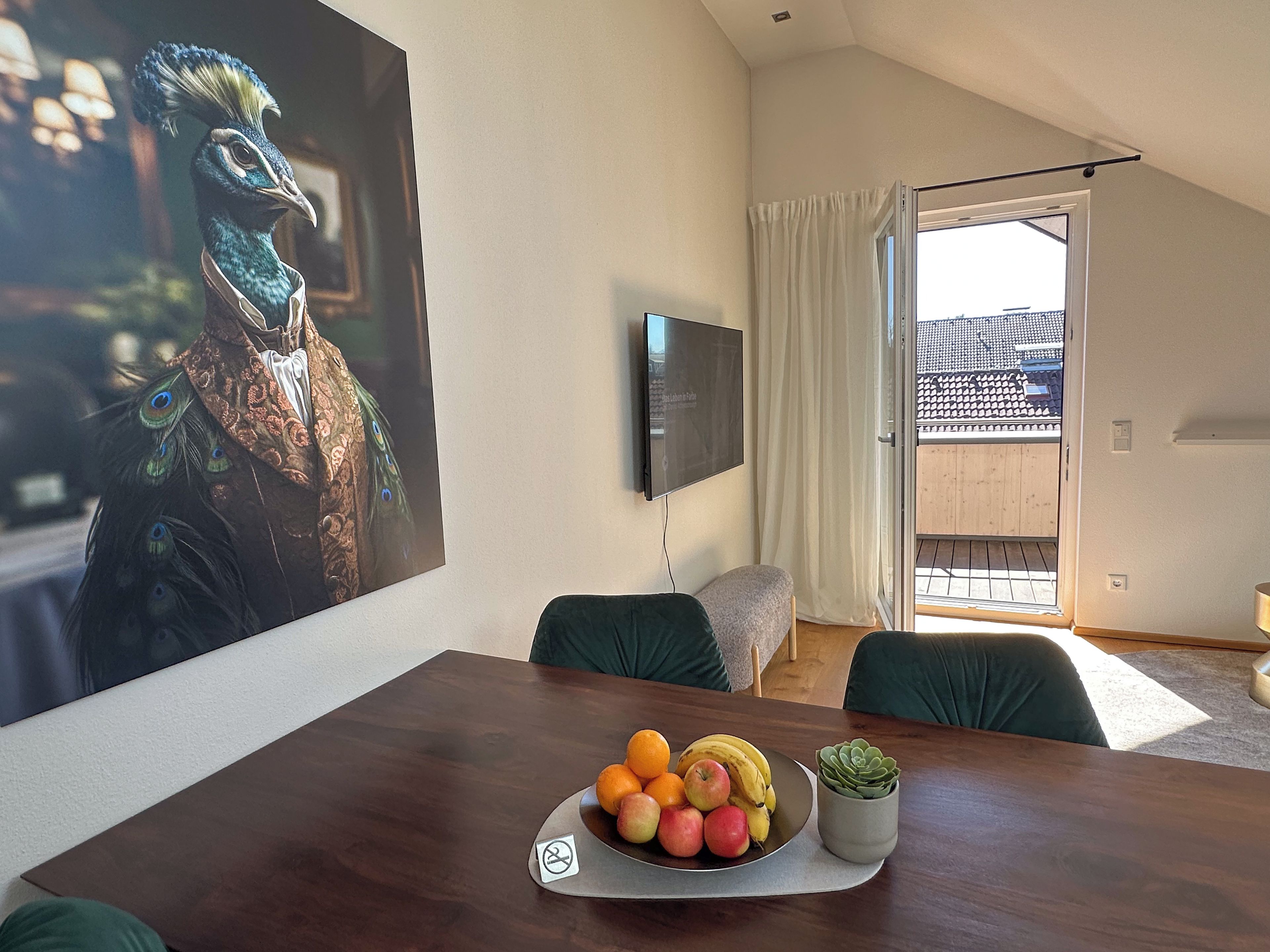 A dining area with a wooden table, a fruit bowl, and a potted plant.