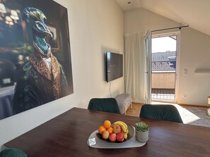 Una zona de menjador amb una taula de fusta, un plat de fruita i una planta en test.