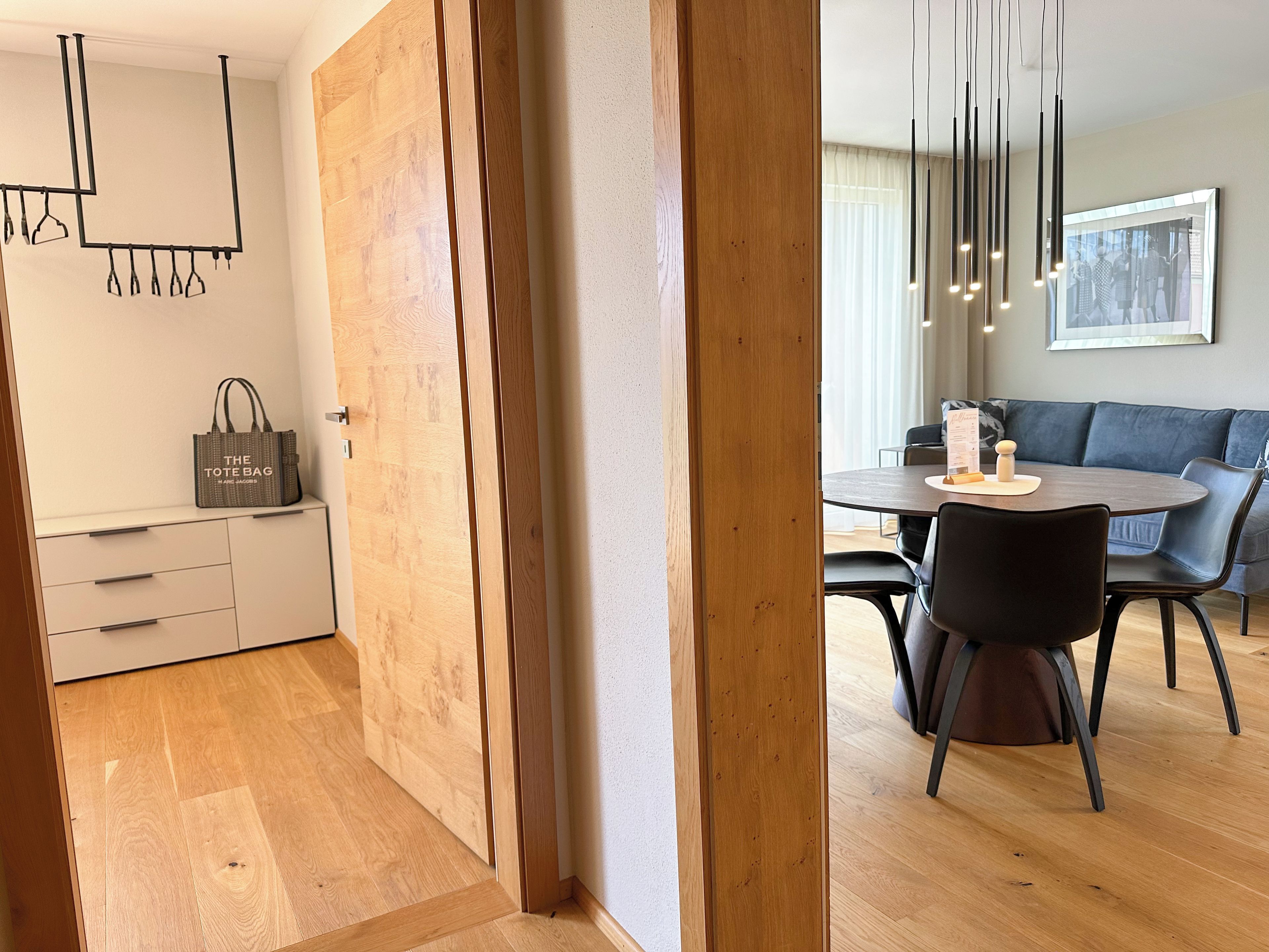 Una cocina moderna con muebles de madera, una lámpara colgante y un comedor con mesa y sillas redondas.