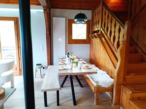 Ein Essbereich aus Holz mit einem für das Frühstück gedeckten Tisch, einer Bank und einer Treppe mit Holzgeländern.