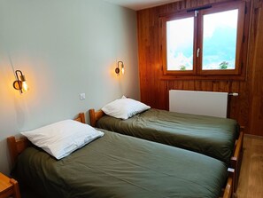 Habitación con dos camas individuales, cabeceros de madera, ventana con vistas e iluminación empotrada.