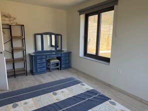 A bedroom with a dresser, a mirror, a window, and a patterned rug. - New, cosy and adult only app in a beautiful village with a lake view (Béznar)